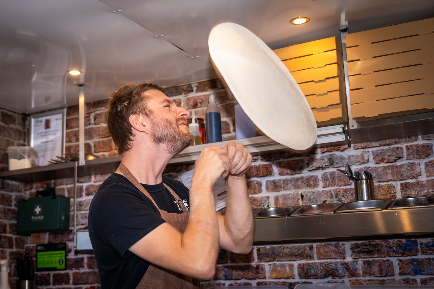 Chris tossing pizza dough in the air inside the Nag Box