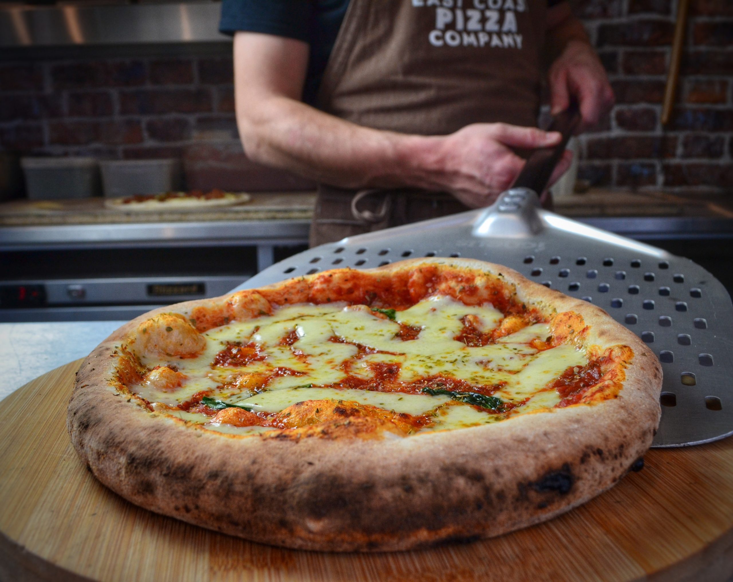 A finished wood-fired pizza fresh out of the oven